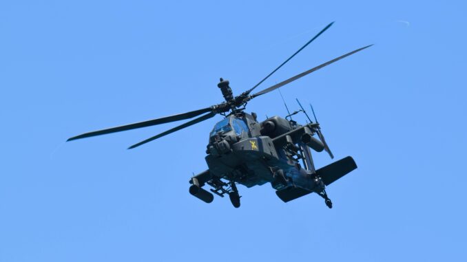 Američki jurišni helikopter AH‑64 Apache u niskom letu – simbol vatrene moći koji Južna Koreja sada povlači iz plana nabavke. Američki jurišni helikopter AH‑64 Apache u letu, snimljen iz blizine u niskom preletu iznad terena, s jasno vidljivim rotorskim krilima i naoružanjem.